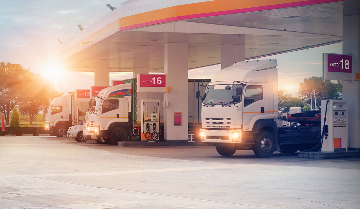 Several trucks fueling up at a convenience store.