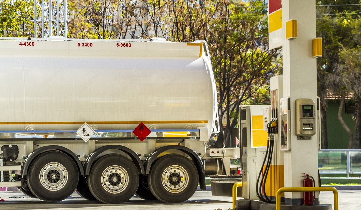 Large tanker truck delivering fuel to a convenience store site.