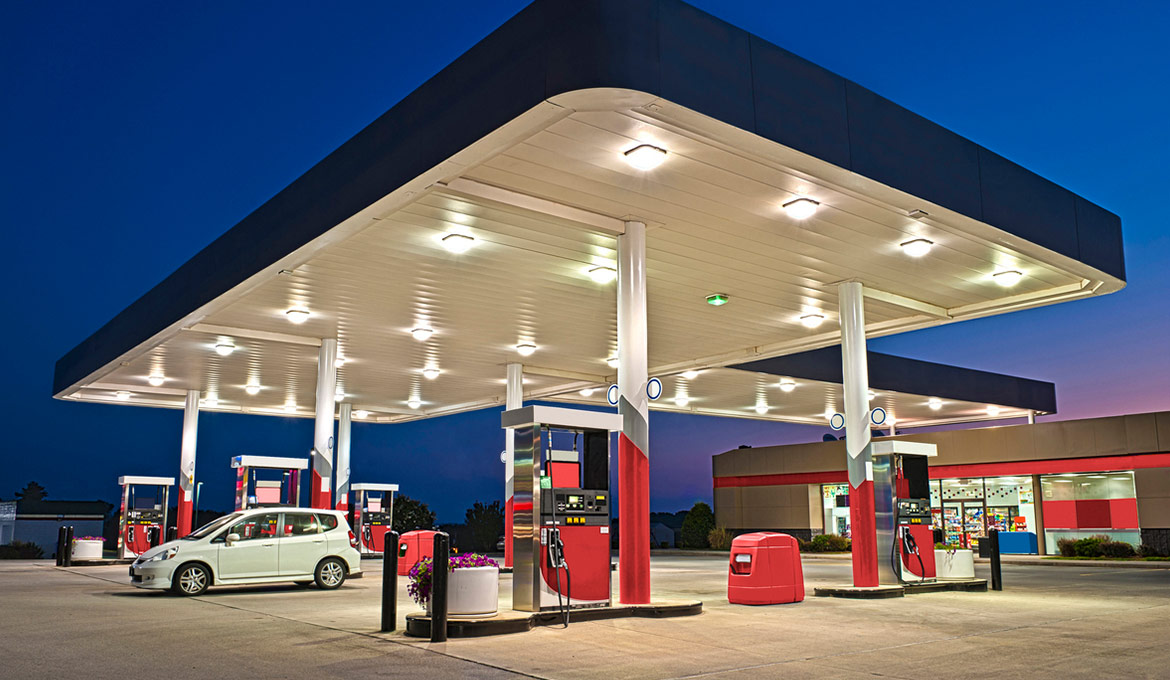 Well lit convenience store and large forecourt at night.