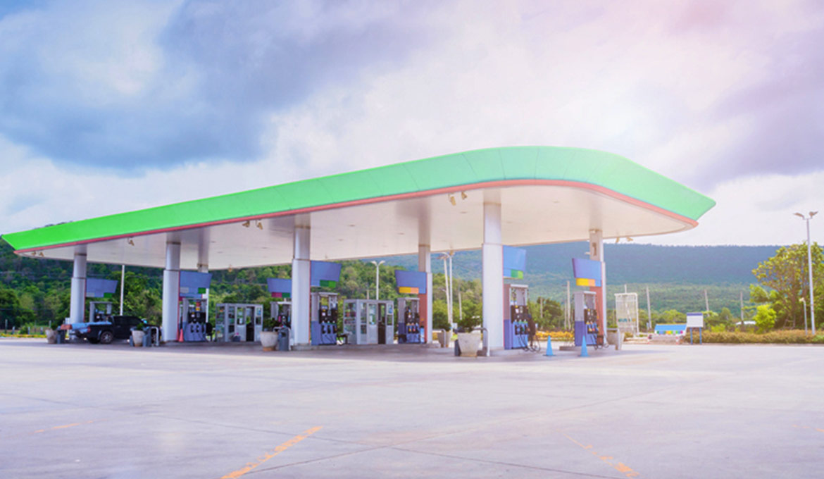 Large forecourt at a convenience store with vehicles fueling up.