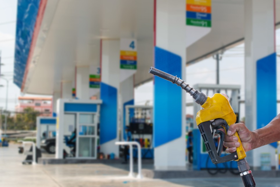 Customer holding up a fuel pump at a convenience store fuel station.