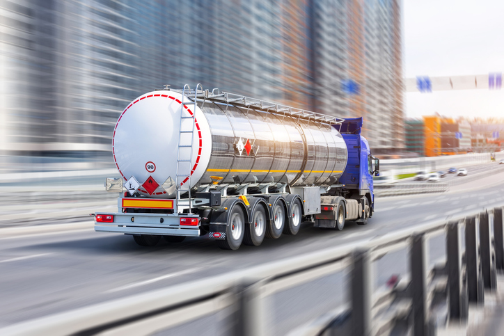 Heavy truck with a chrome metal cistern driving along the street.