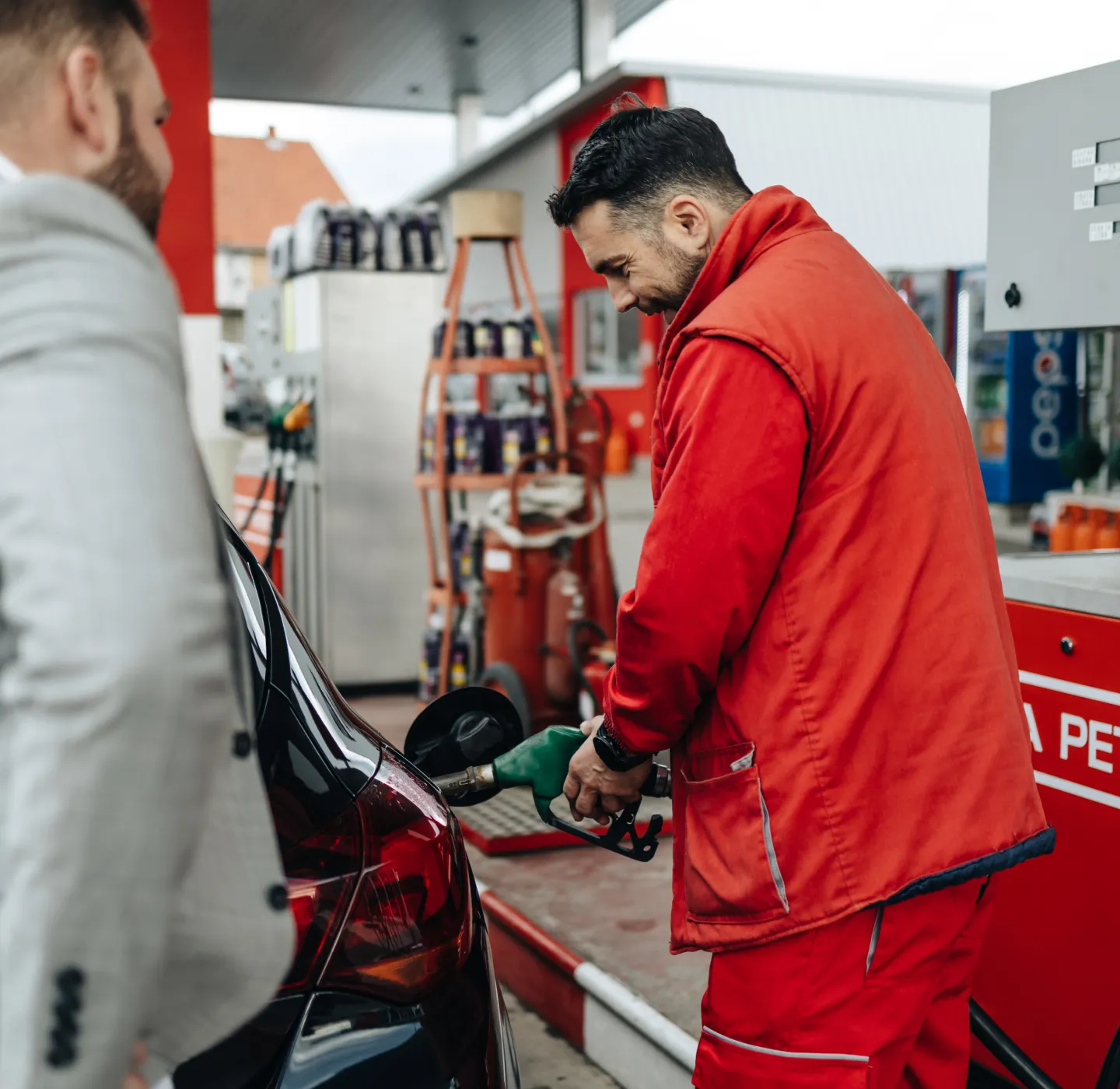 Gas station worker fueling up a car for a customer.