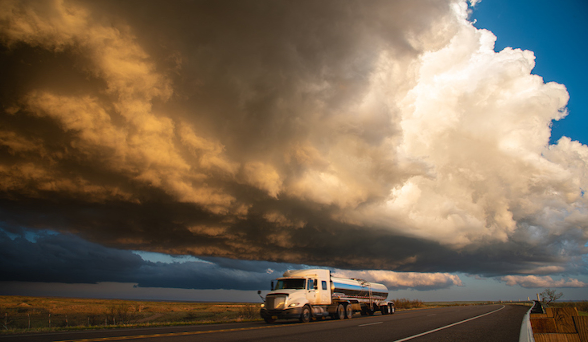 Fuel tanker on the highway passing under severe weather clouds.